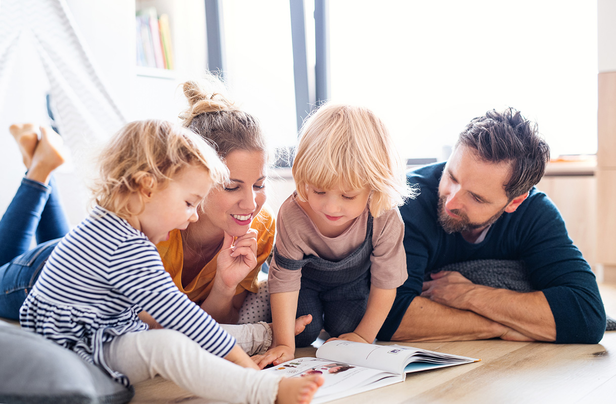 A family gathered on the floor around a book, reading together with comfortable and clean indoor air quality.