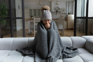 woman in winter hat and blanket cold at home