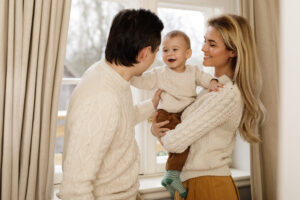 Young and happy family at home  standing beside the window